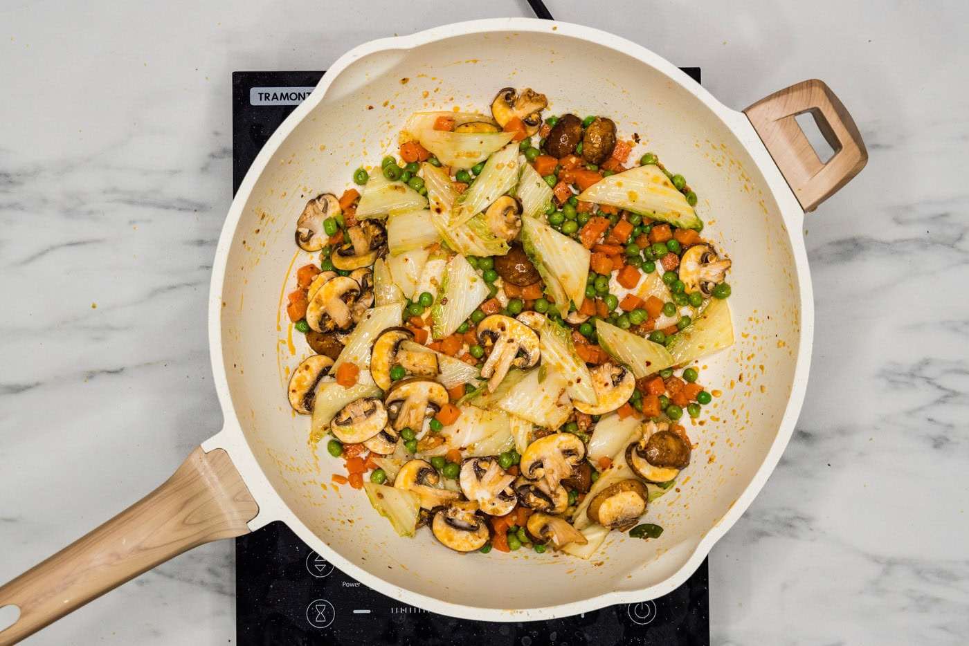 stir fried cabbage, carrots, and peas in a skillet