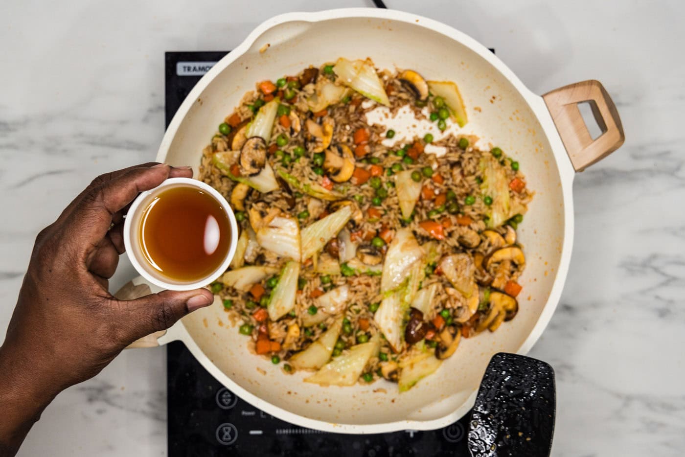 adding sesame oil to skillet of stir fried korean rice