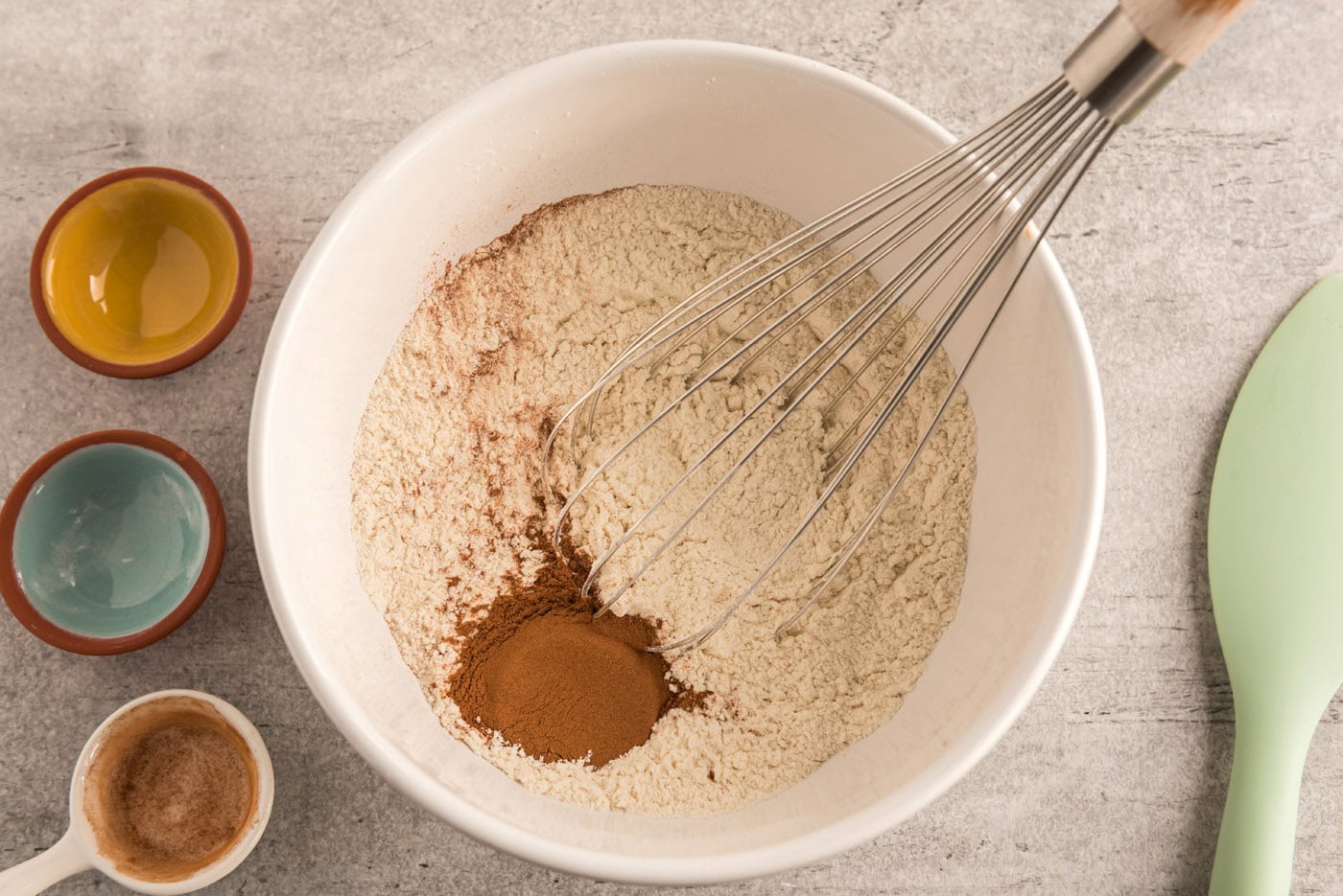 cinnamon added to dry ingredients for cookie dough in a bowl with a whisk