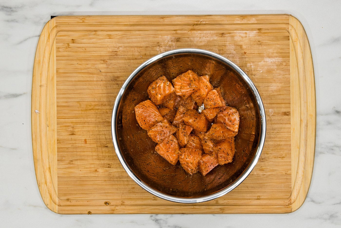 salmon cubes in a bowl with olive oil and seasonings