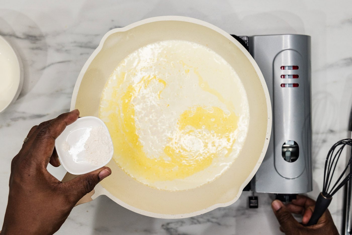 adding flour to skillet of half and half and butter