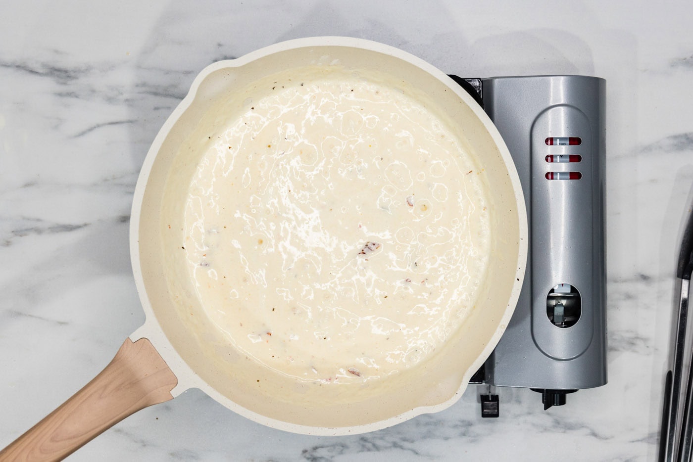 sun dried tomatoes added to cream sauce in a skillet