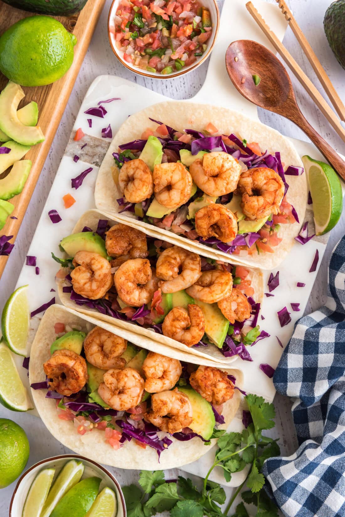 Three Shrimp Tacos surrounded by limes and pico