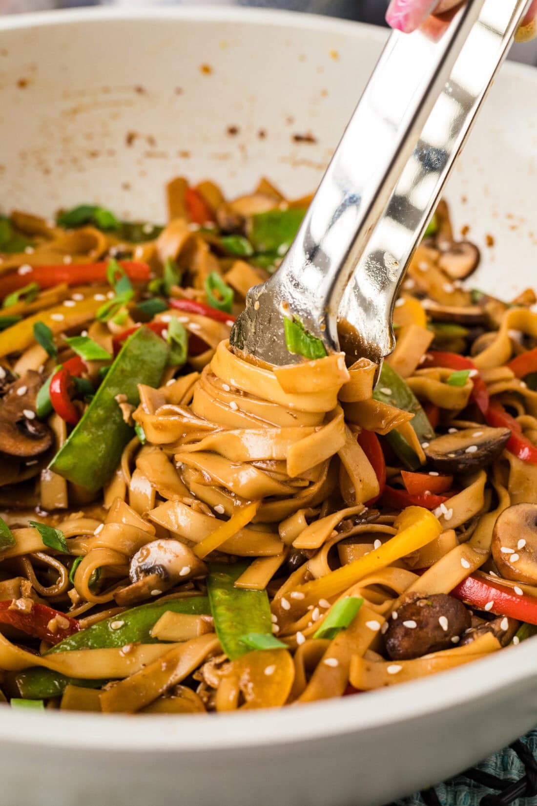 Tongs twisting Vegetable Lo Mein in a skillet