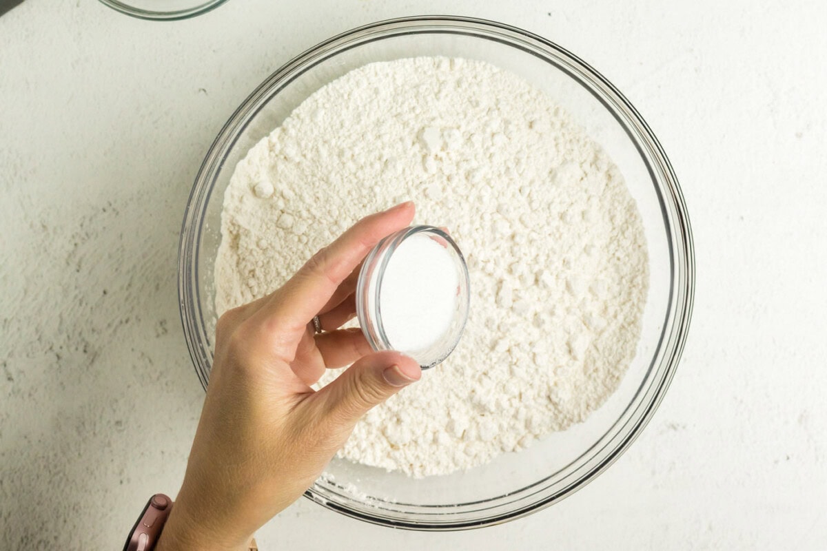 Sugar being added into a bowl of flour