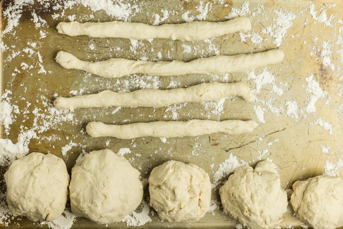 Ropes of dough and dough balls on a floured baking sheet