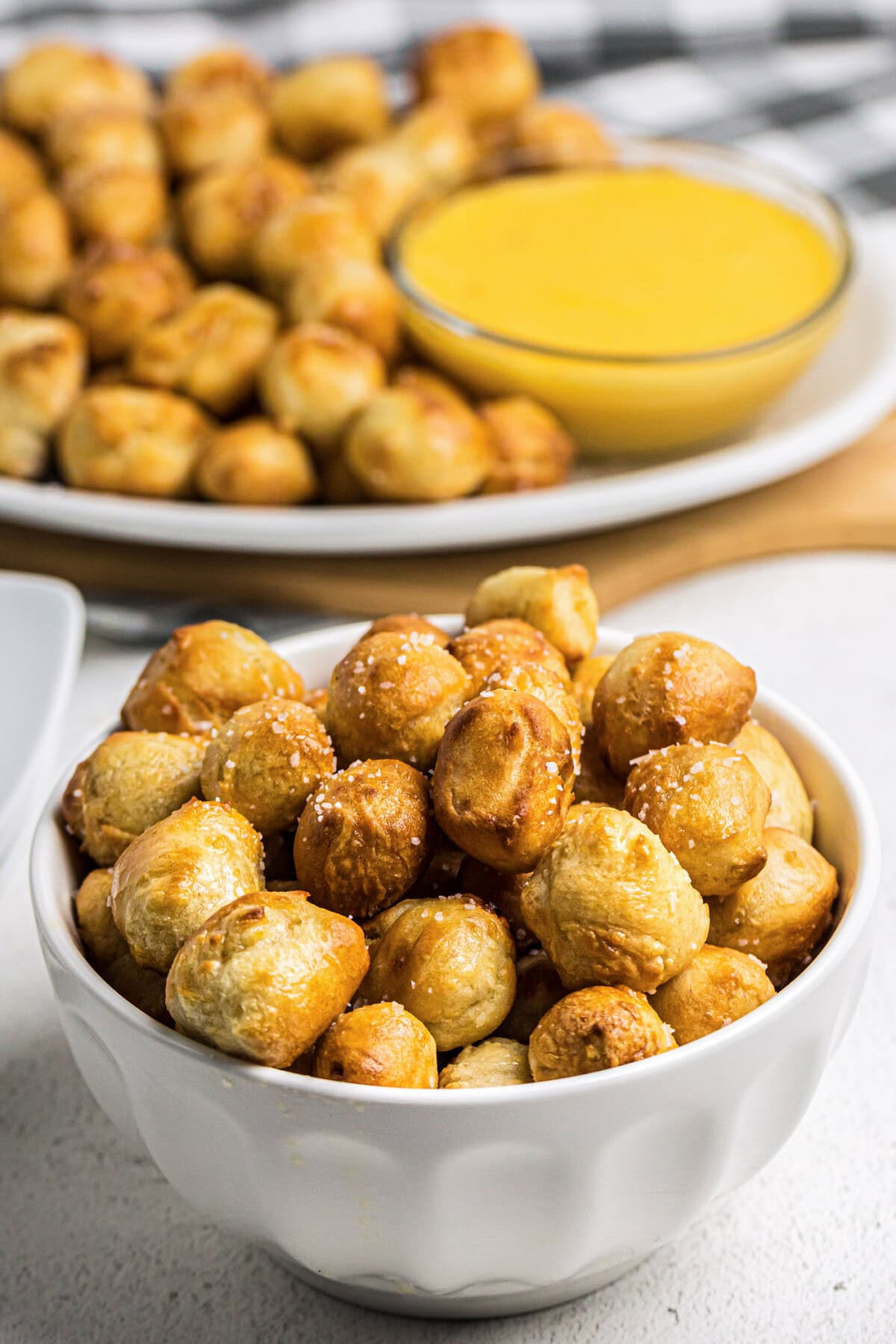 Bowl of Air Fryer Pretzel Bites with more pretzel bites on a platter in the background
