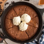Brownies in a Cast Iron Skillet cut into slices topped with ice cream