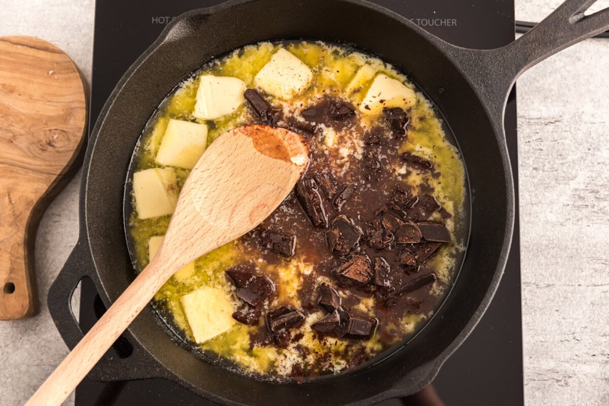 chopped chocolate and butter in a cast iron skillet with wooden spoon