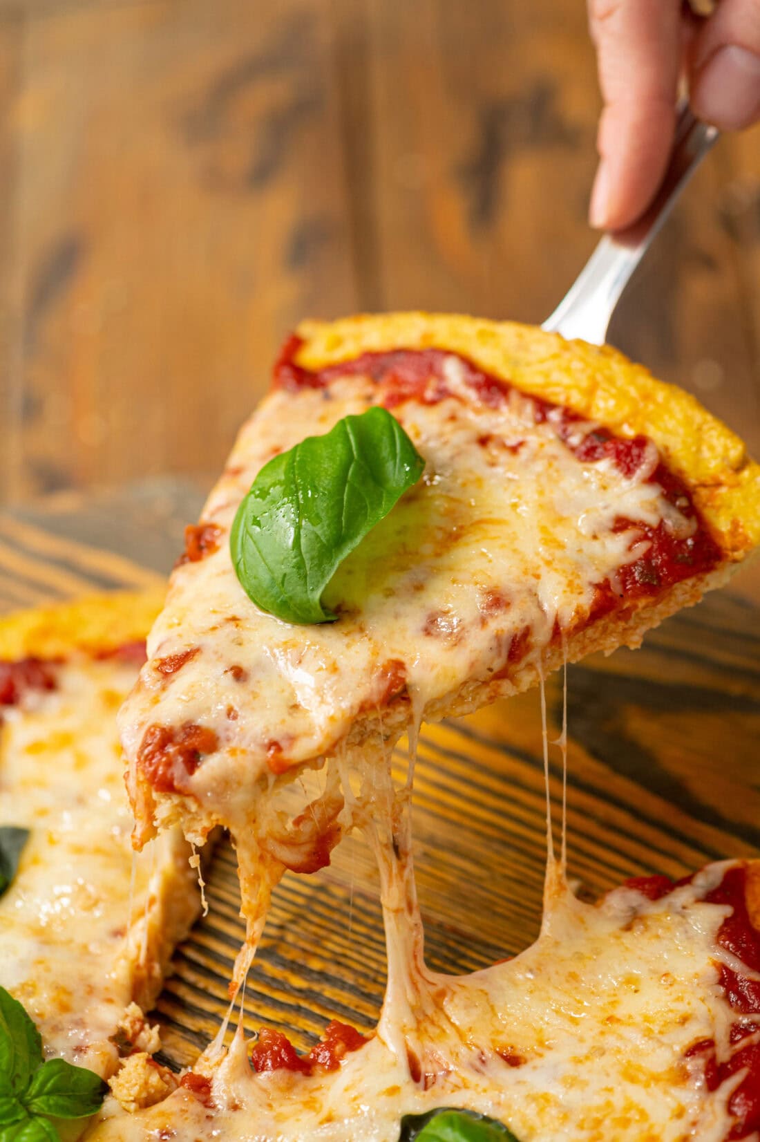 Slice of Cauliflower Pizza Crust pizza being lifted up from the platter