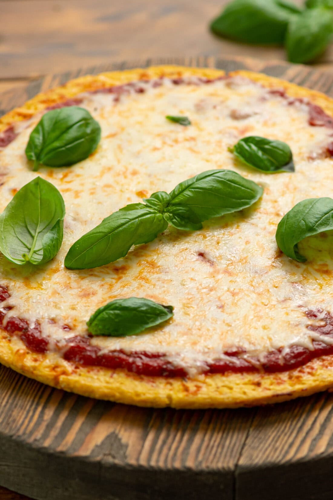 Cauliflower Pizza Crust pizza topped with basil leaves