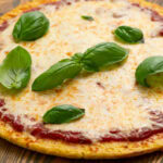 Cauliflower Pizza Crust pizza topped with basil leaves