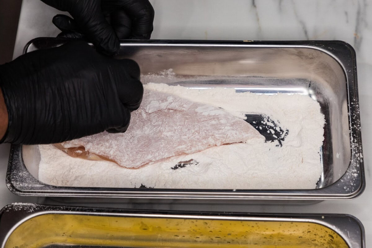 dipping chicken breast into flour