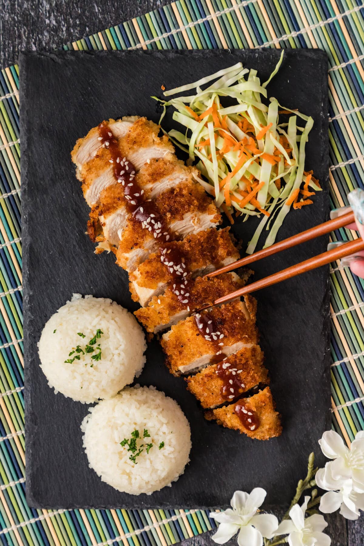 Chopsticks reaching for a slice of Chicken Katsu