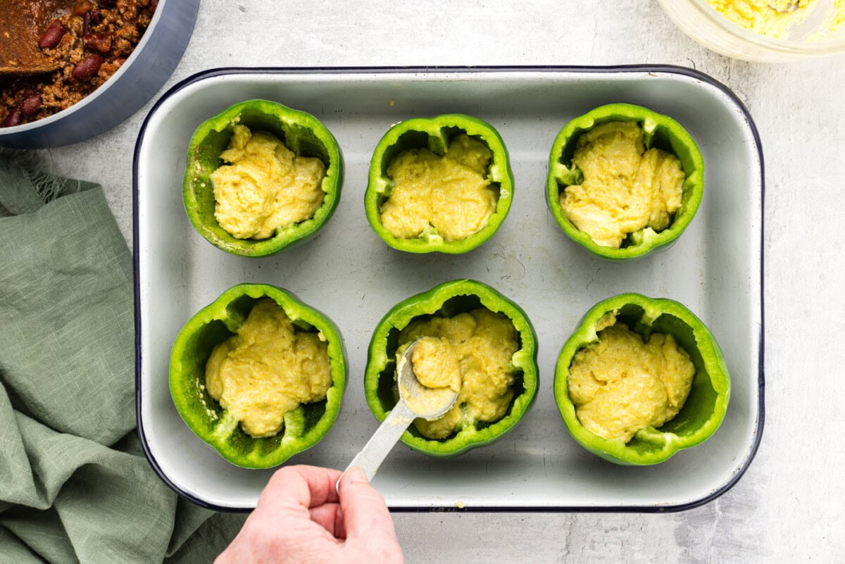 spooning cornbread batter into hollowed out bell peppers