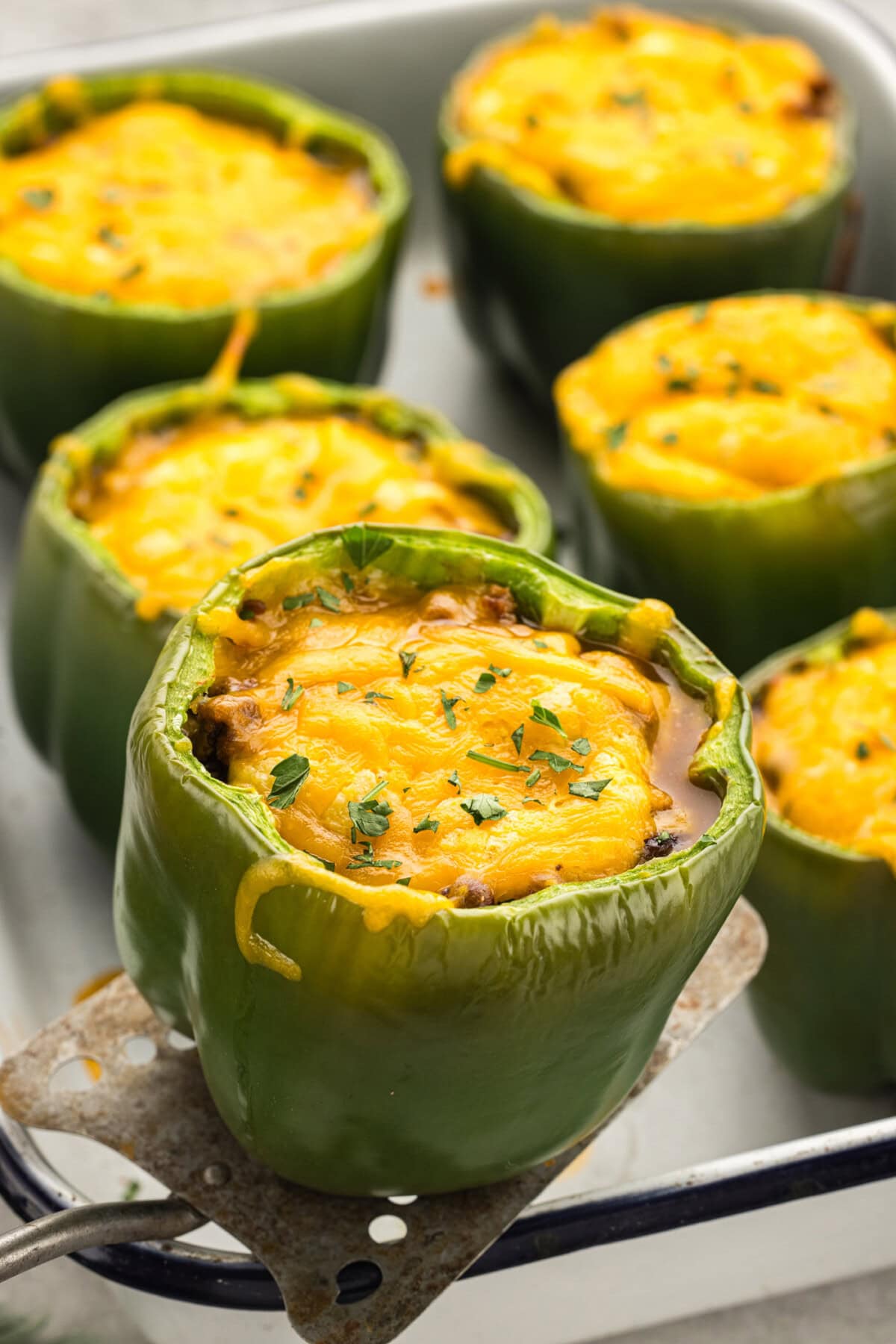 Chili and Cornbread Stuffed Pepper being lifted out of the pan