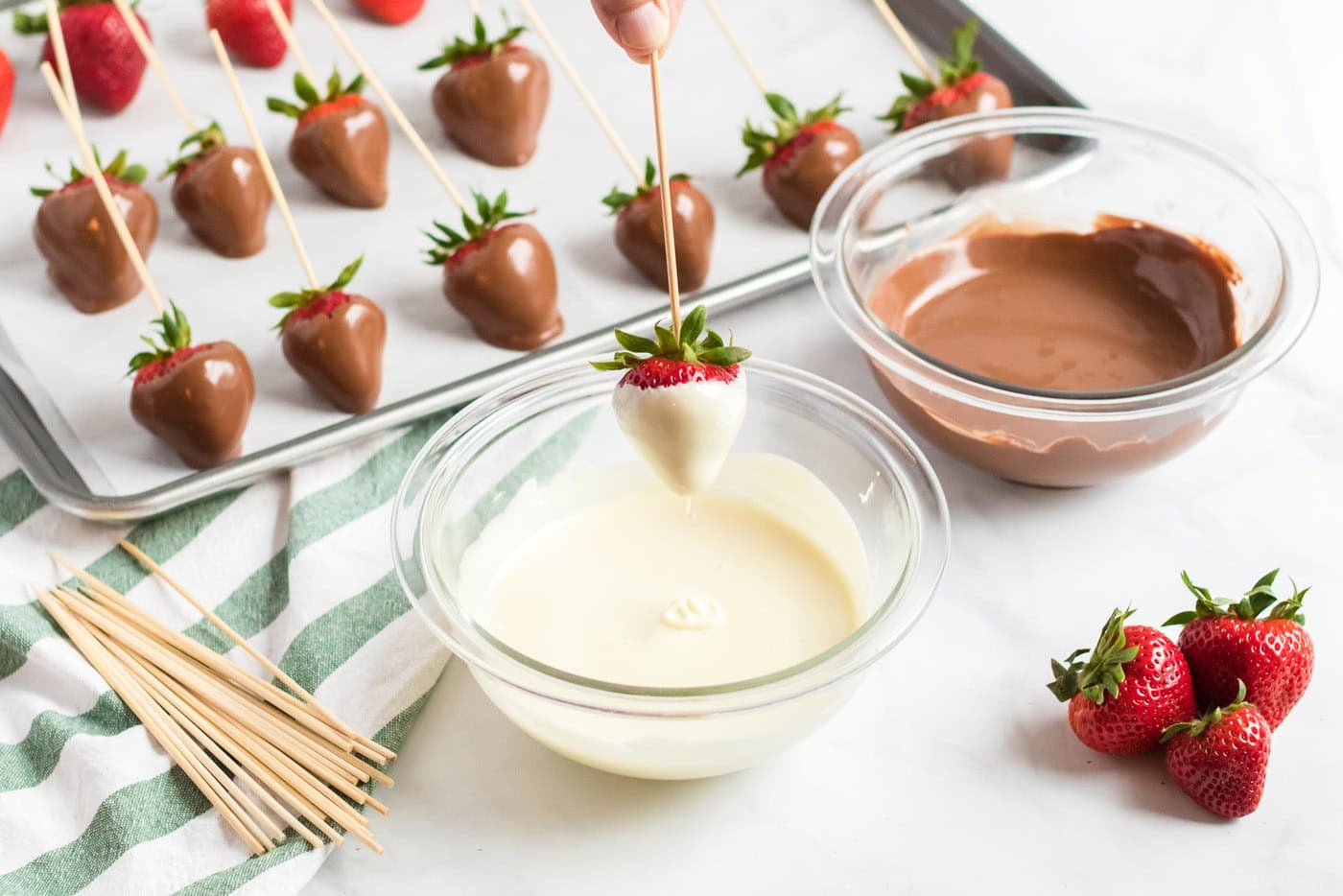 dipping a strawberry into melted chocolate