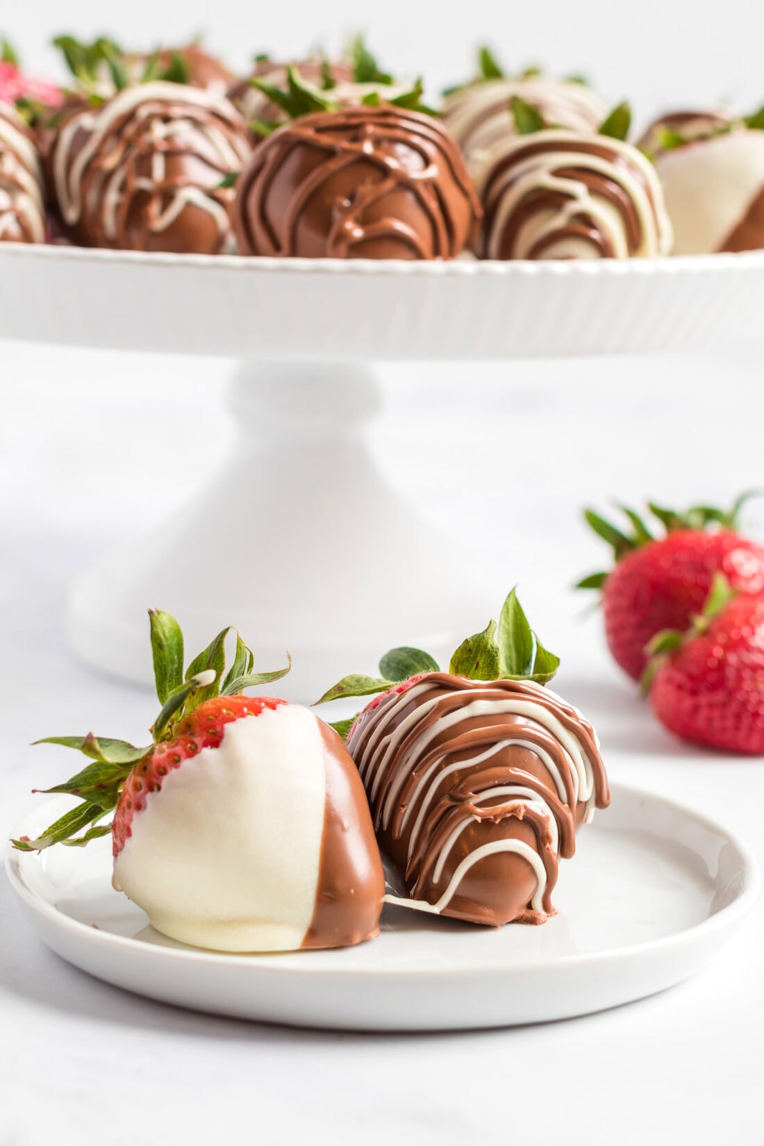 Two Chocolate Covered Strawberries on a plate with more in the background