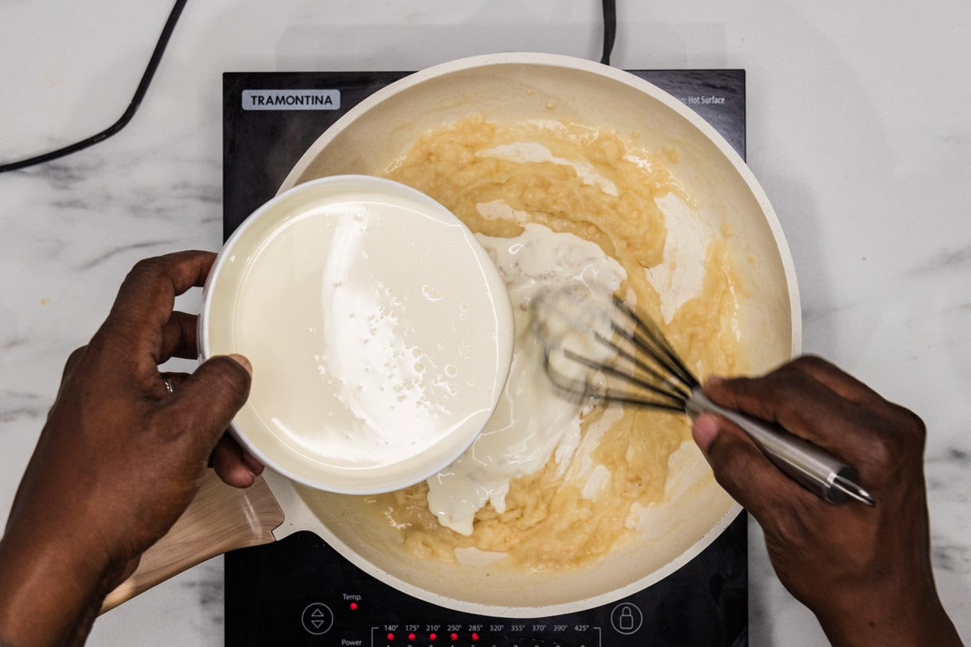 whisking heavy whipping cream into skillet with lemon and garlic mixture