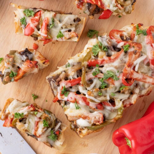 Slices of Philly Cheesesteak Cheesy Bread on a wooden cutting board