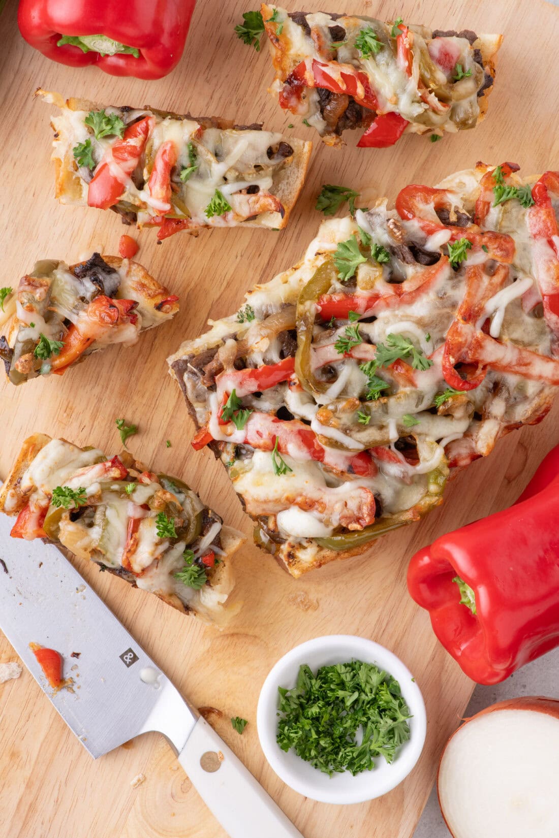 Philly Cheesesteak Cheesy Bread cut into slices on a wooden cutting board