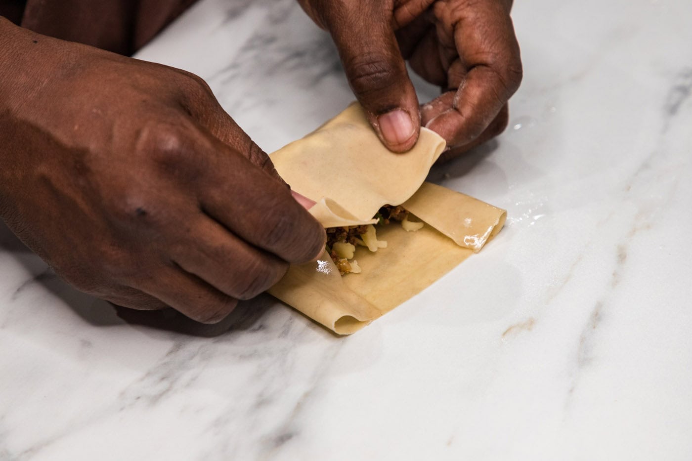 hands folding egg roll wrapper