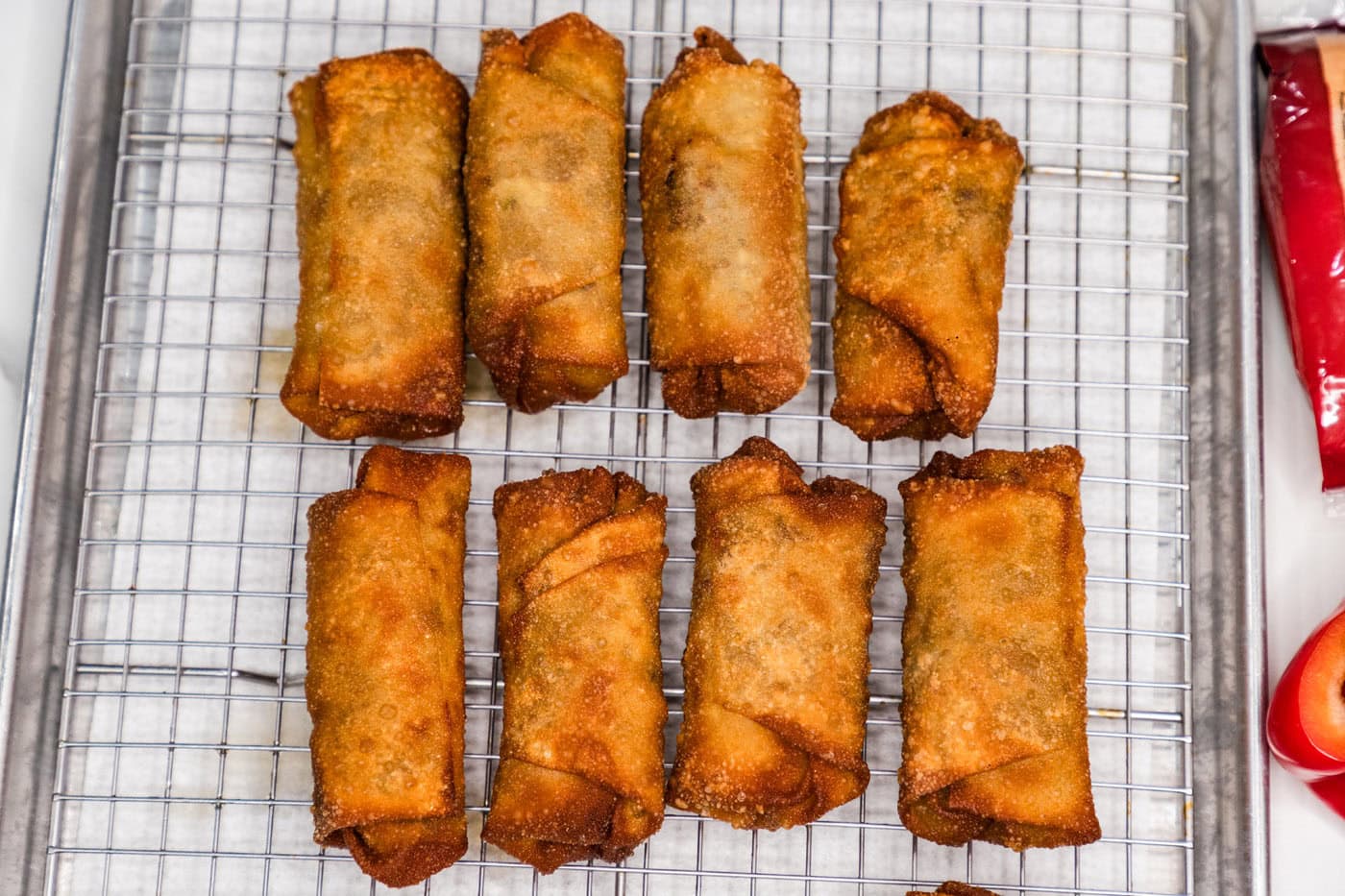 fried philly cheesesteak egg rolls on a wire rack