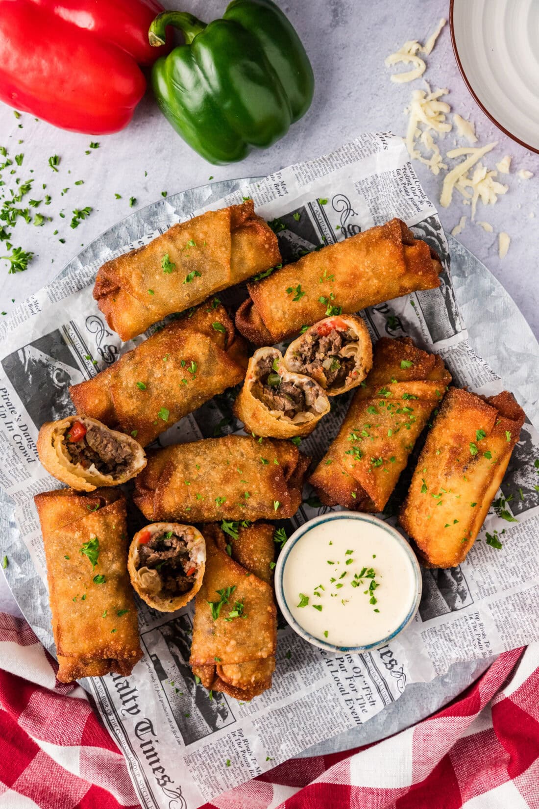 Platter of Philly Cheesesteak Egg Rolls with a bowl of cheese sauce on the side