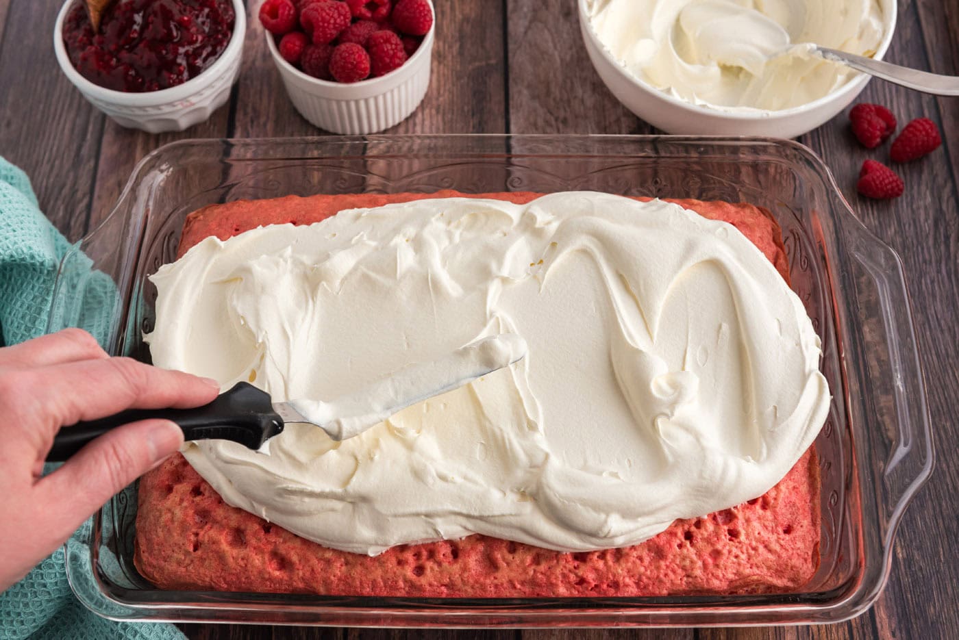 spreading cool whip over raspberry cake