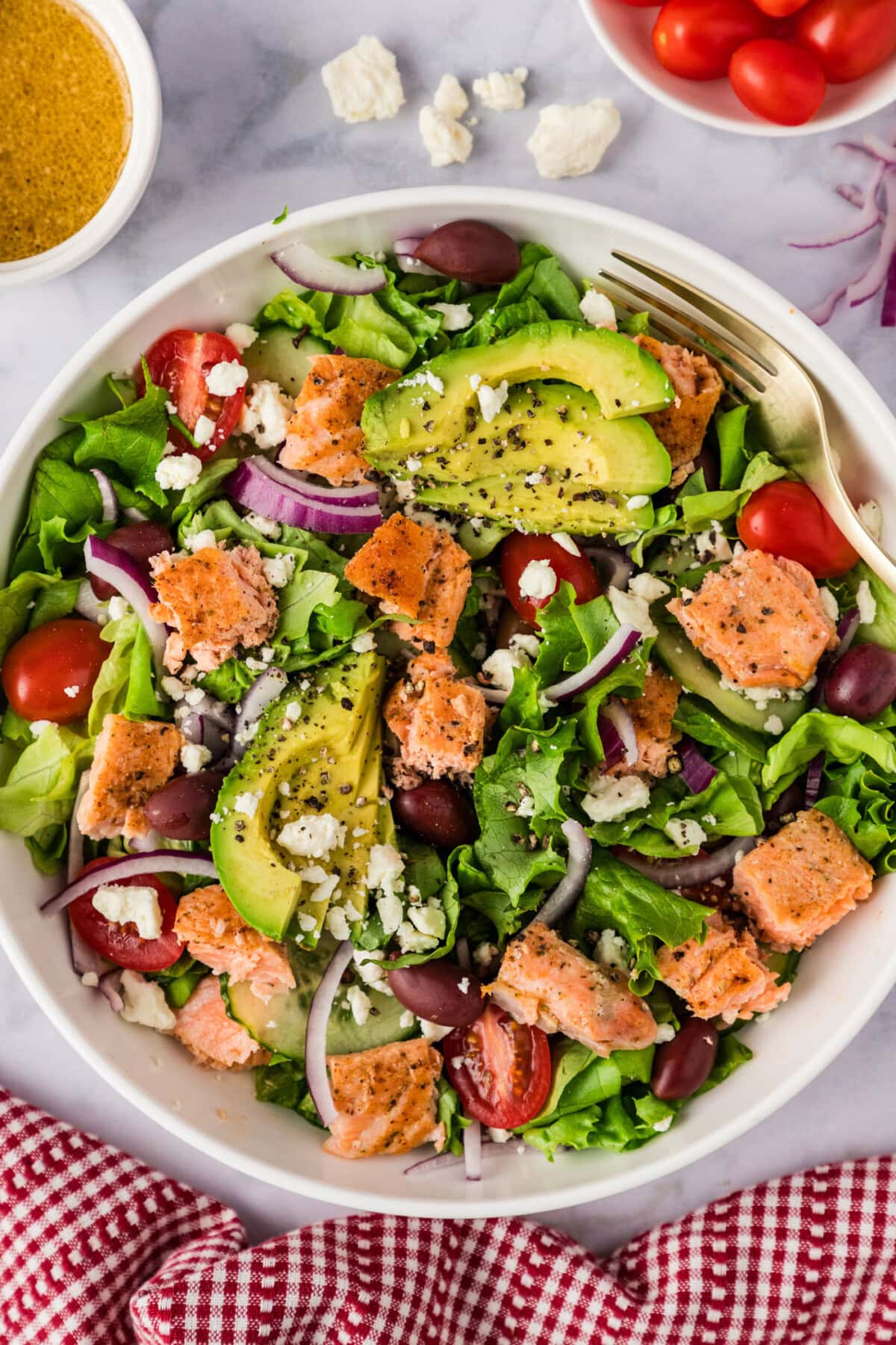 Bowl of Salmon Salad with tomatoes, dressing and feta to the side