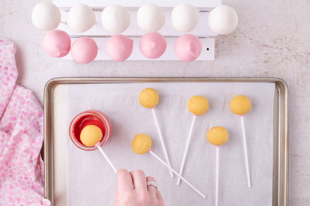 dipping cake pop into red chocolate
