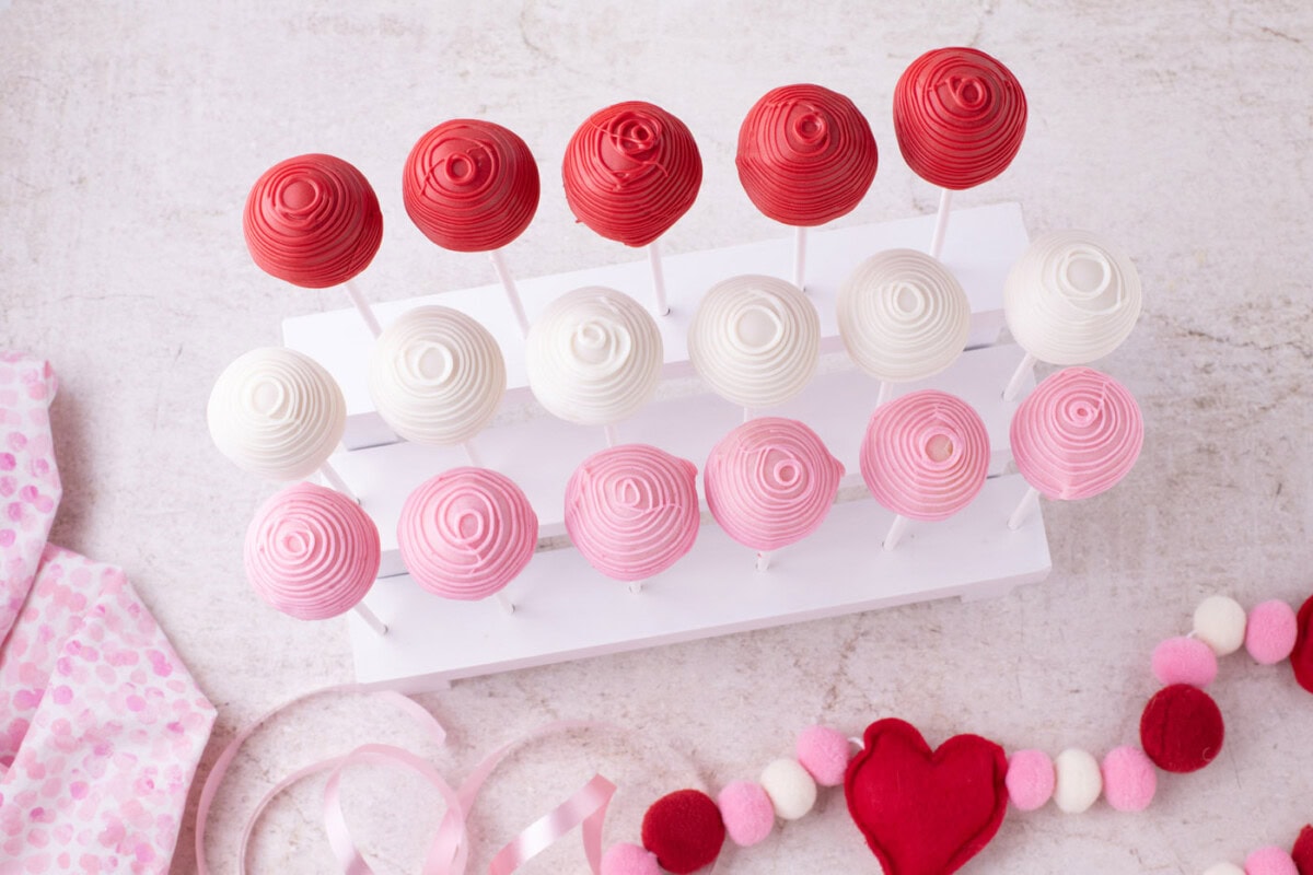 overhead of drizzled cake pops on a stand