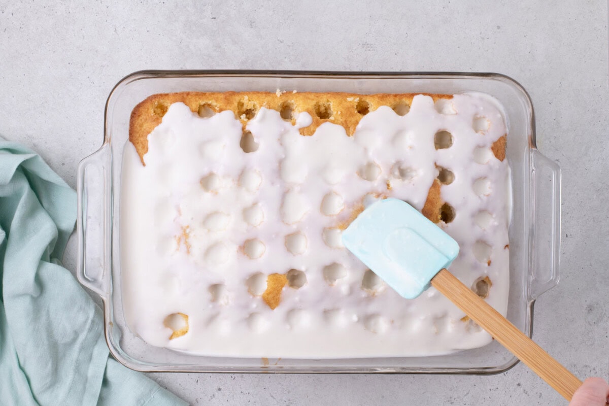 spreading coconut cream filling over holes in a cake