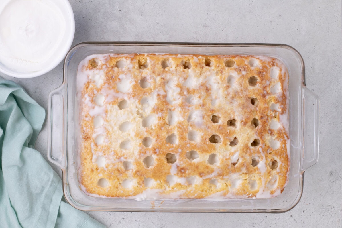 coconut cream filling poured over holes in a cake
