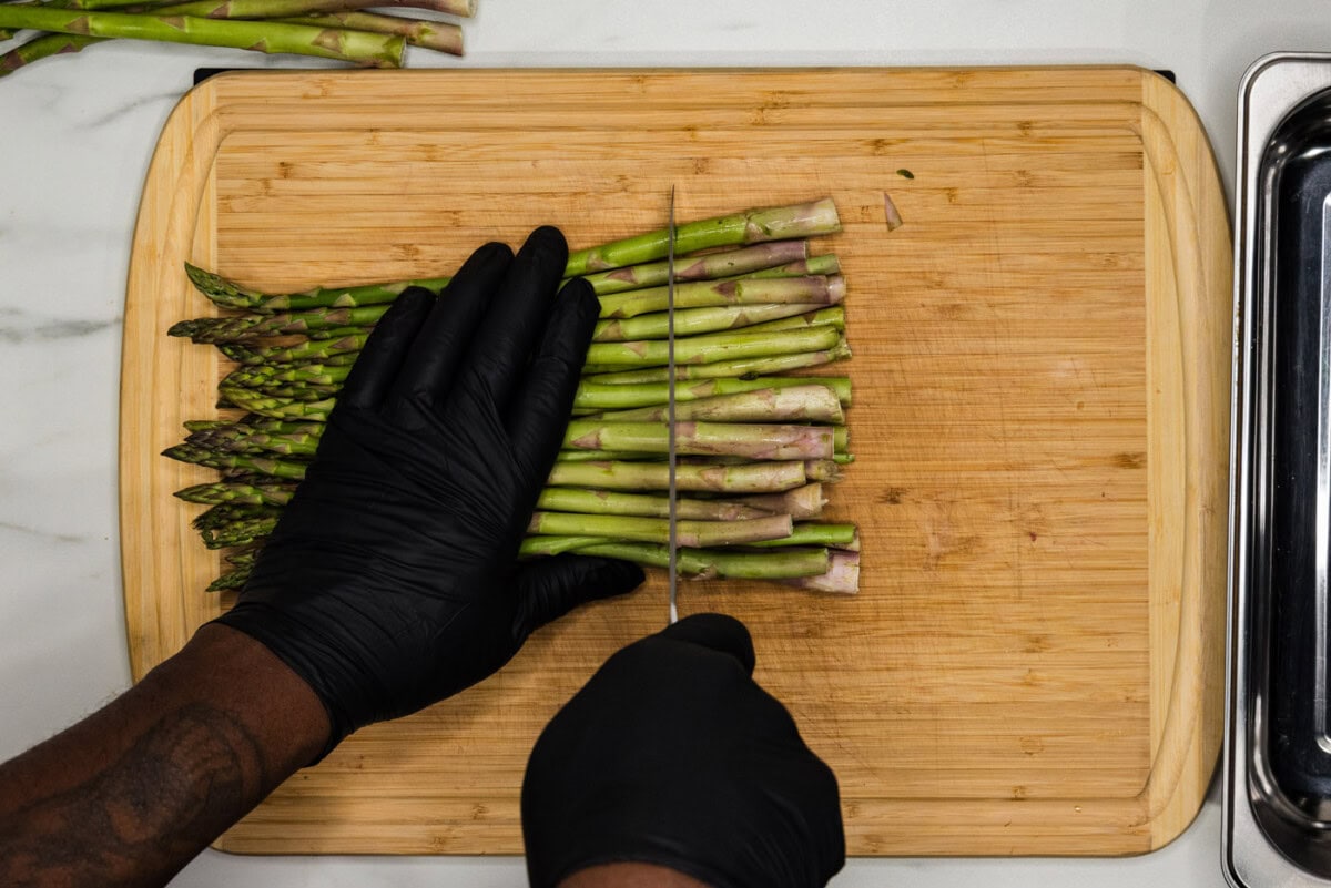 knife cutting woody ends off asparagus