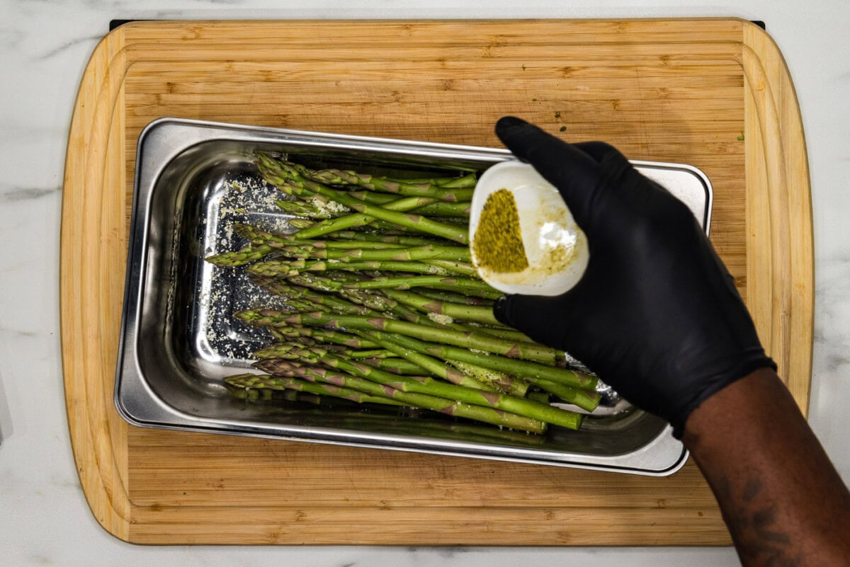 seasoning asparagus in a pan with lemon pepper