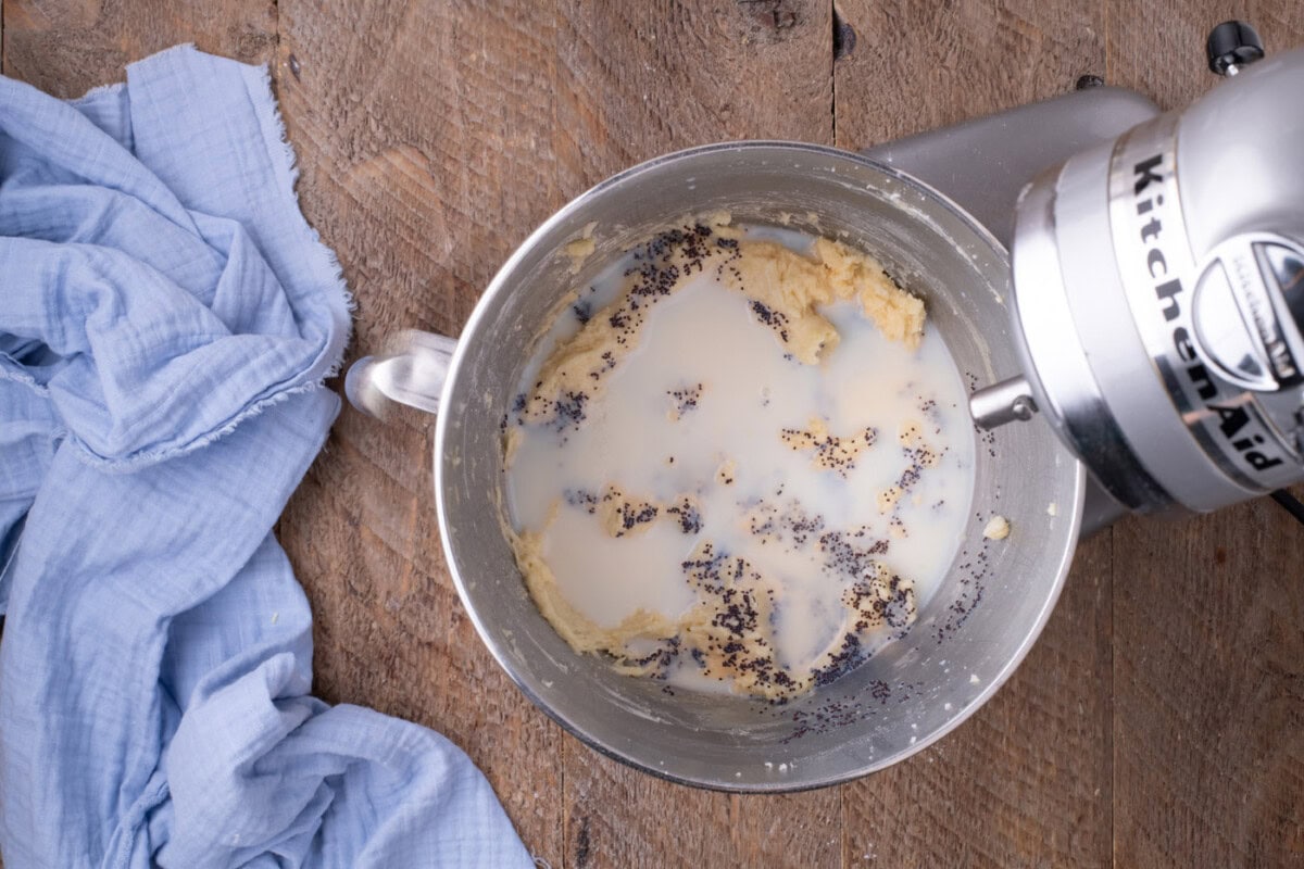 poppyseeds and buttermilk added to lemon cake batter in a stand mixer