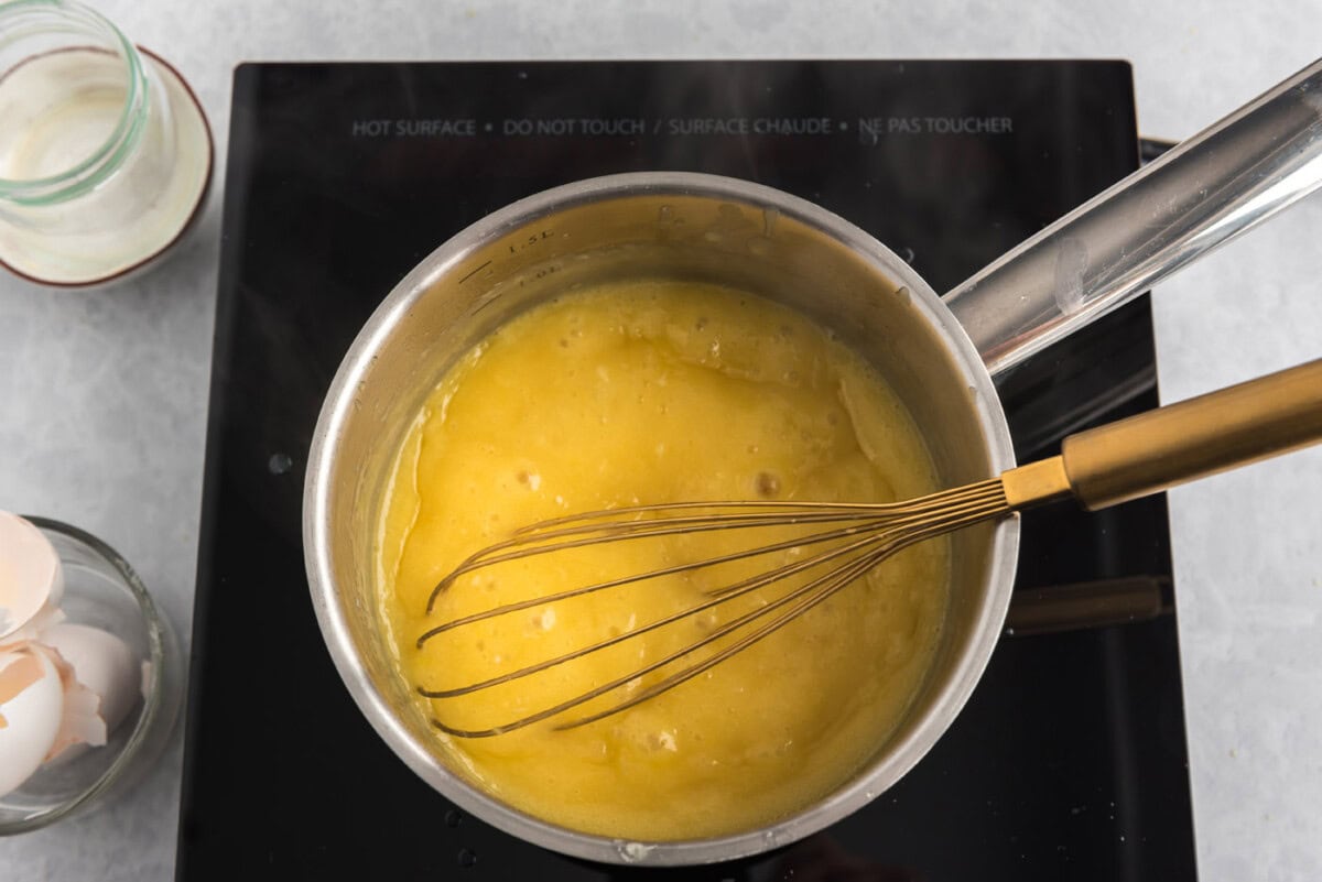 homemade lemon curd in a saucepan with a whisk