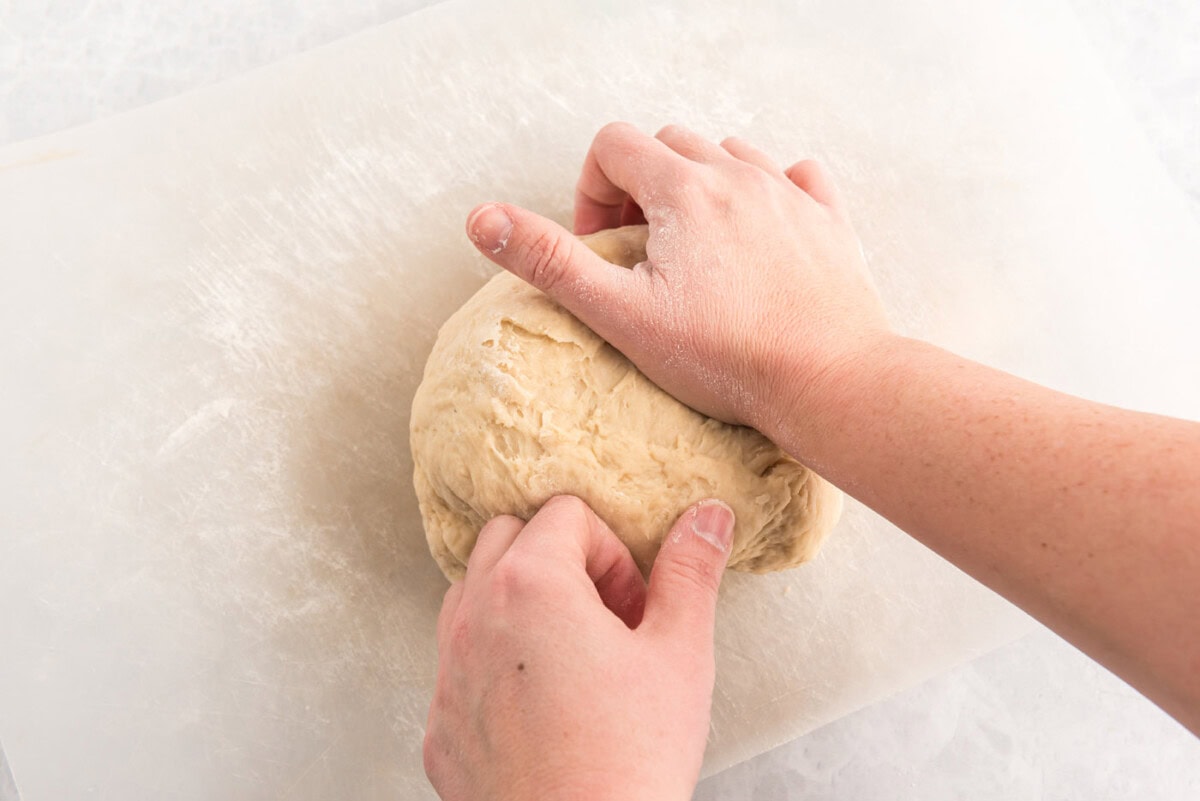 hands kneading dough ball