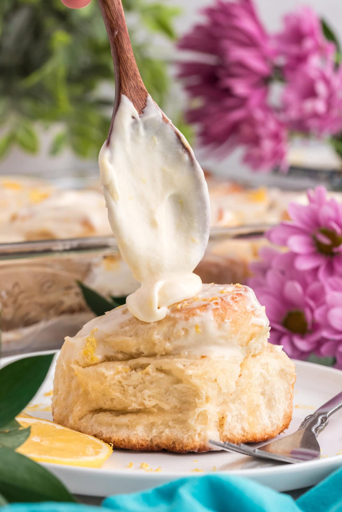 Lemon frosting being dropped onto a lemon sweet roll