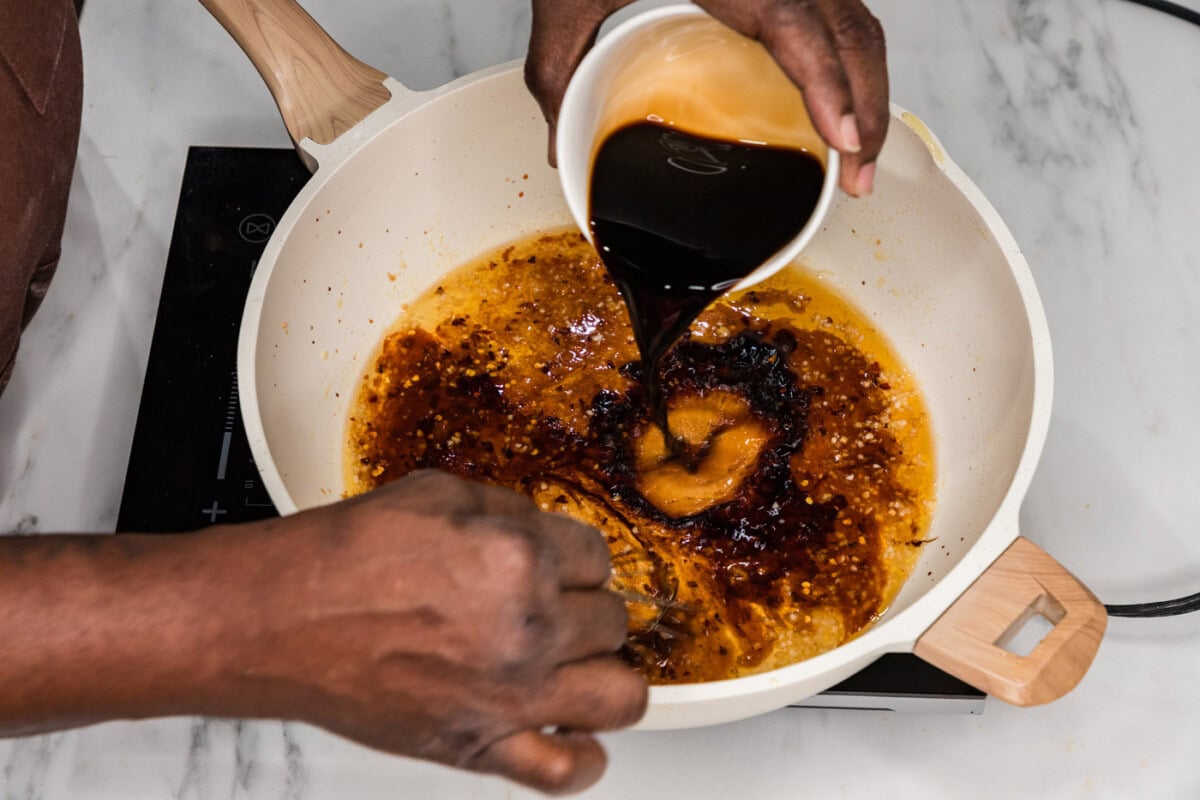 whisking oyster sauce into sauce in a skillet