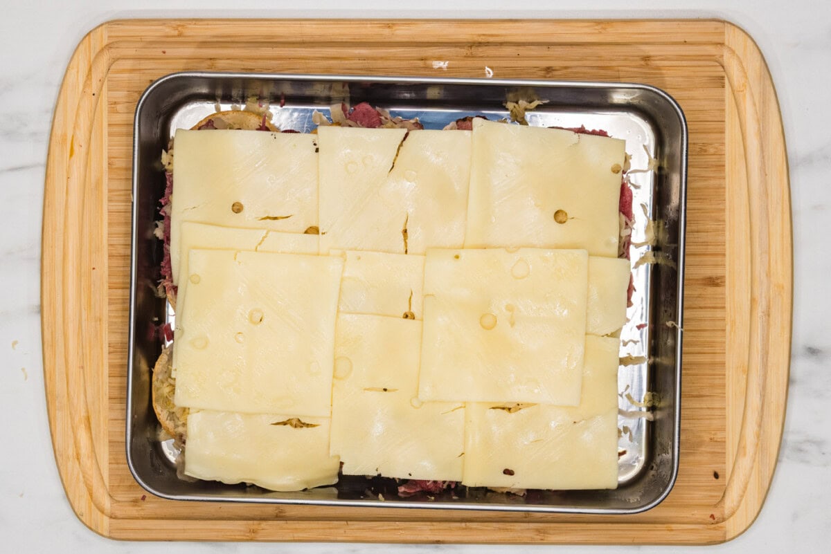 Swiss cheese on top of corned beef and sauerkrat