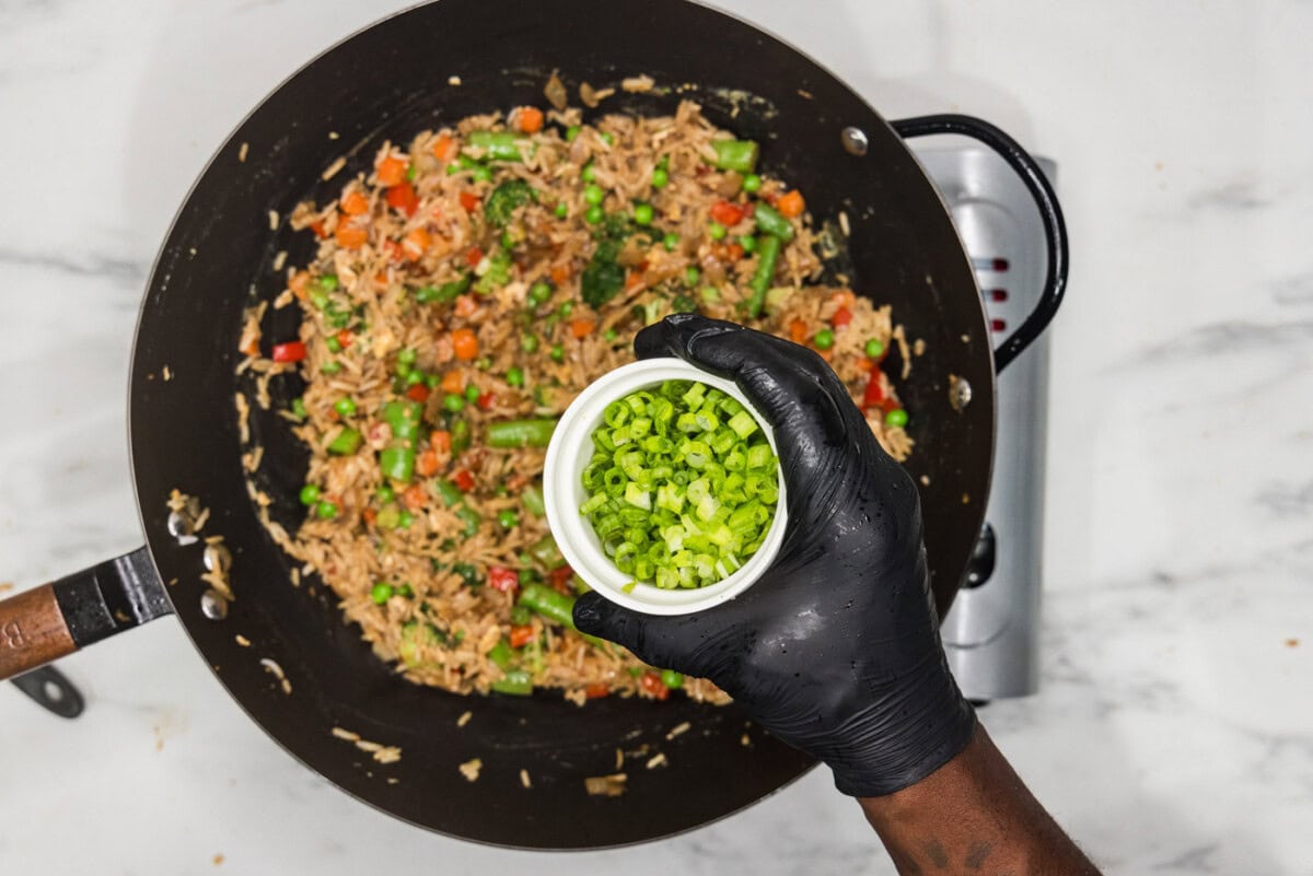 sliced green onions in a bowl over vegetable fried rice