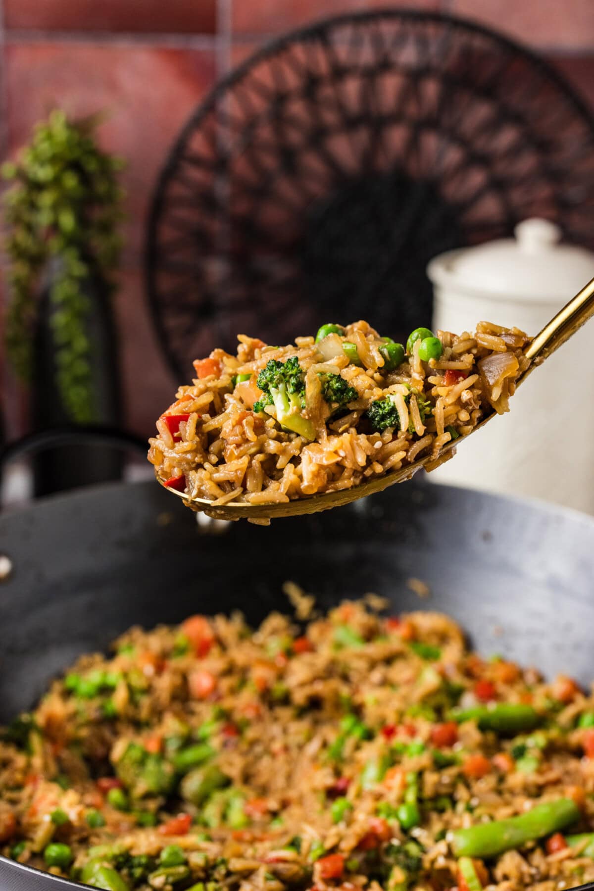 Spoonful of Vegetable Fried Rice held above a wok of Vegetable Fried Rice