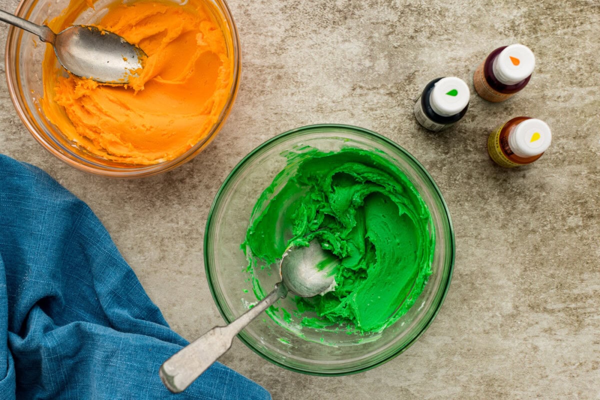 green and orange tinted cream cheese frosting in a bowl