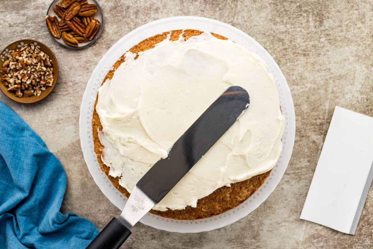 icing spatula spreading frosting over cake