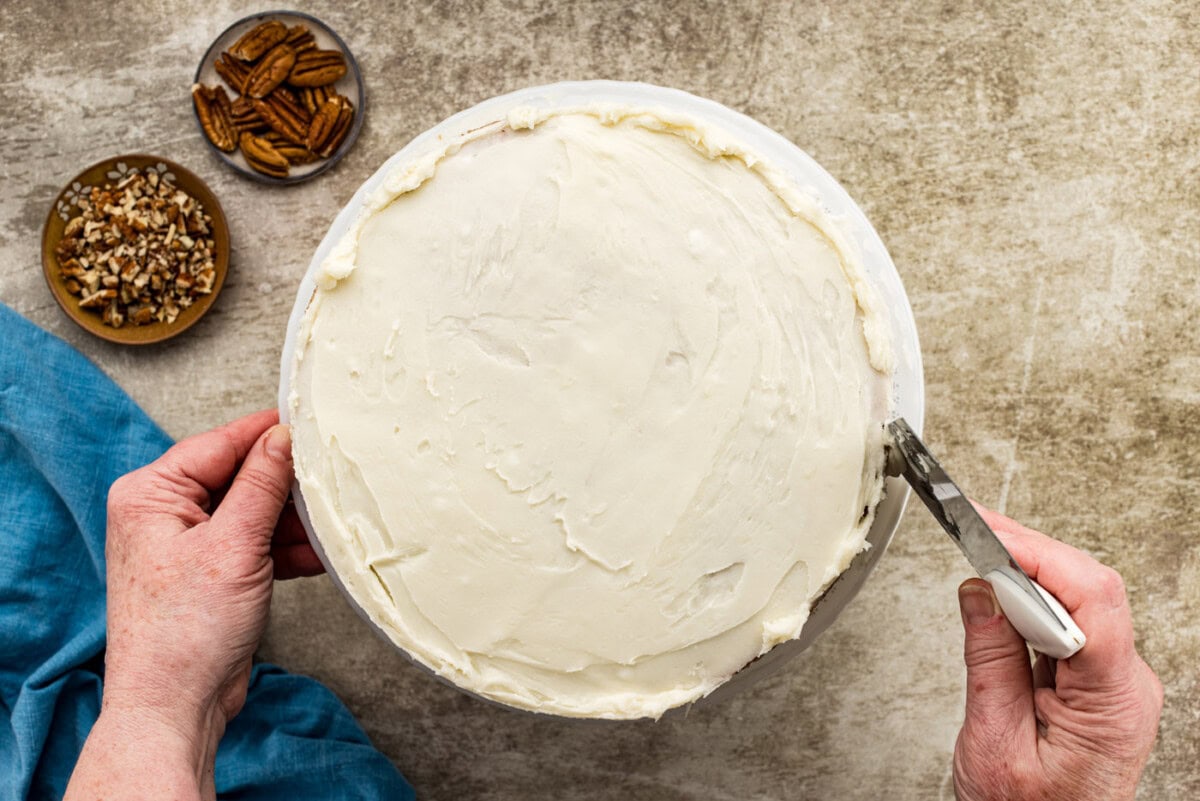 bench scraper removing excess frosting from cake