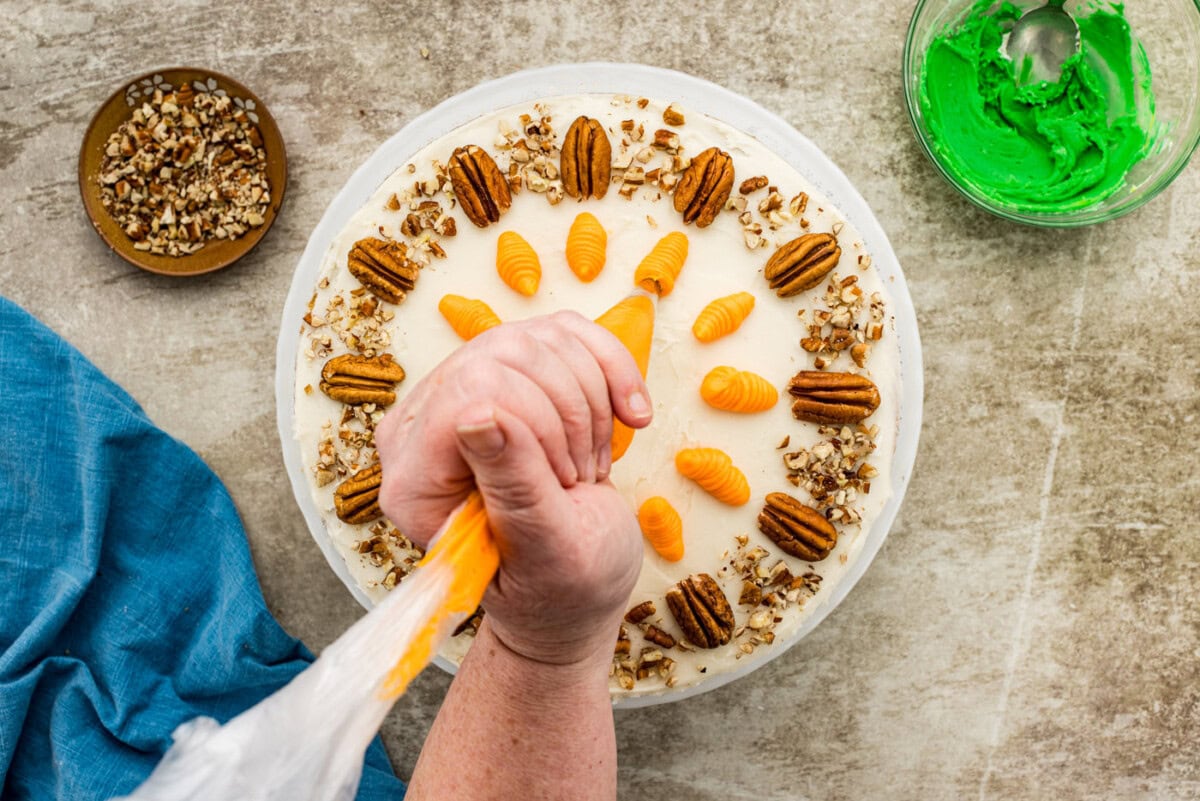 hand piping carrots onto cake