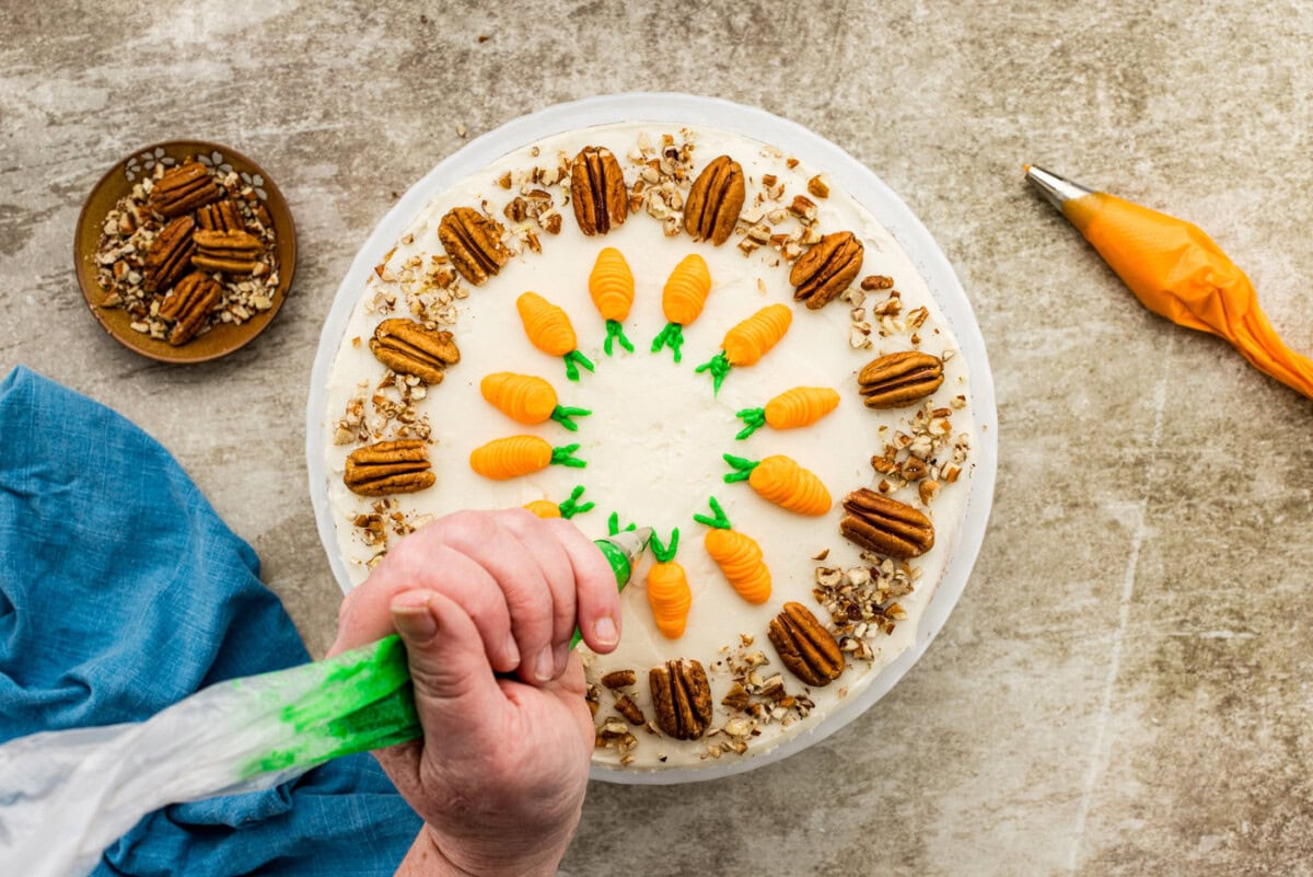 piping green leaves onto carrot cake
