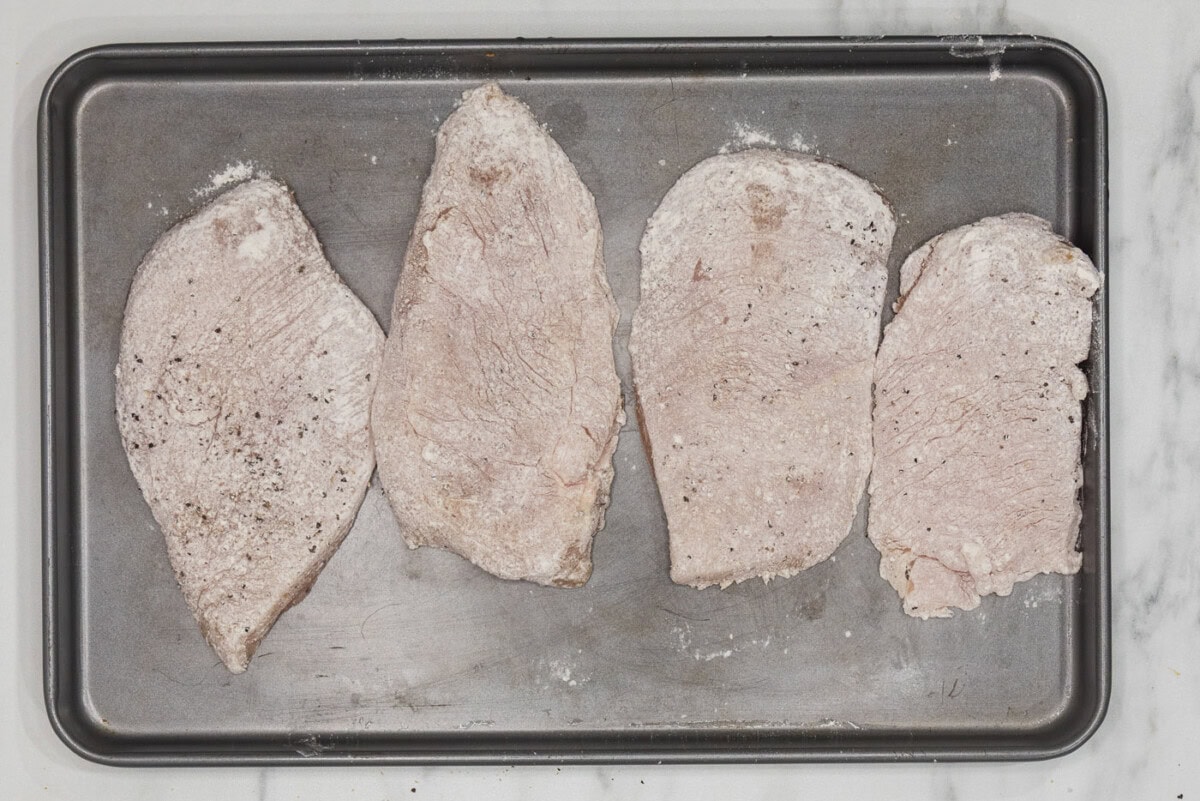 flour dredged chicken on a baking sheet